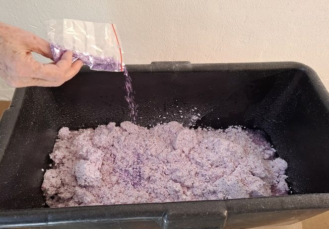 Dekorgestaltung Eine Hand gibt Glitzer zum Baumwollputz im Eimer