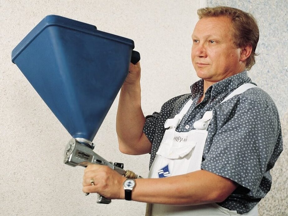 Arbeiter mit einer blauen Trichterspritzpistole in der Hand